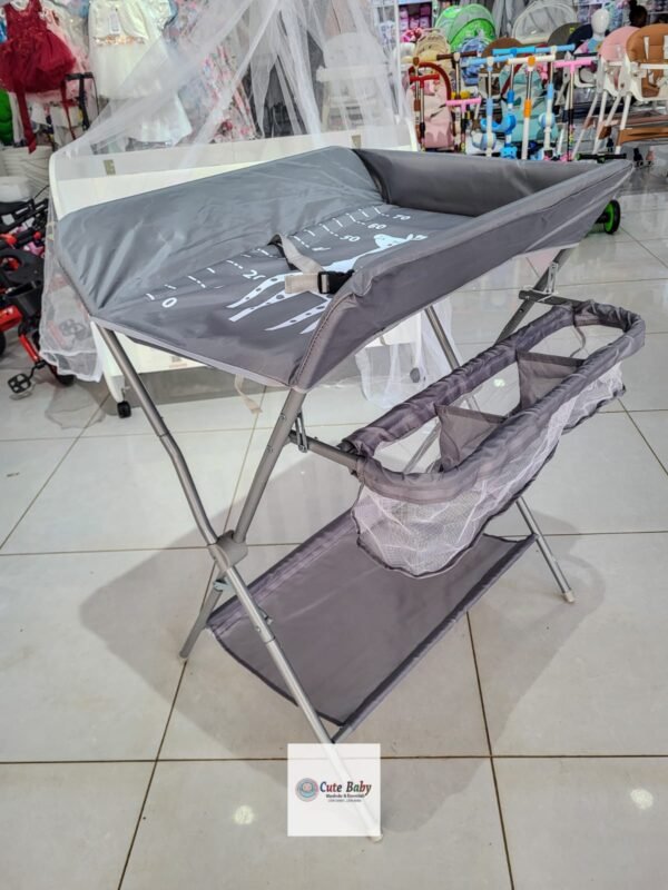 Grey folding baby changing station with side storage and a lower shelf