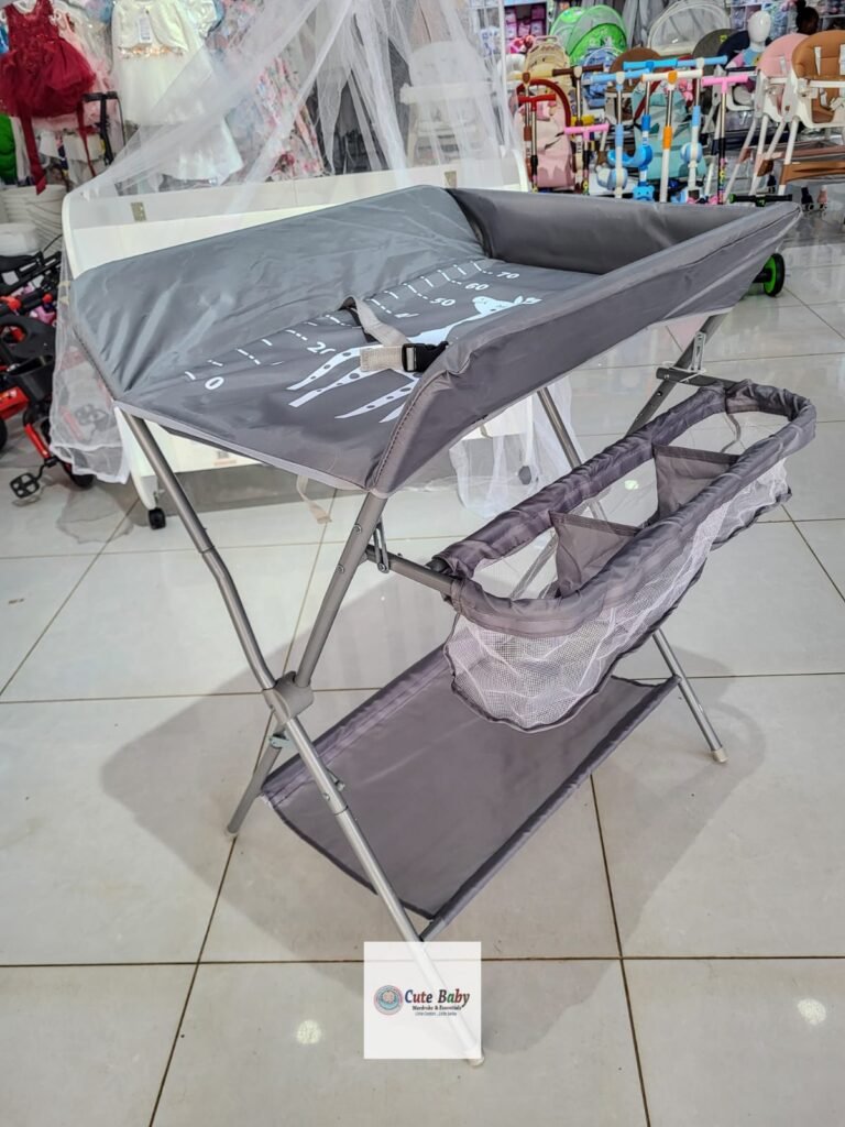 Grey folding baby changing station with side storage and a lower shelf